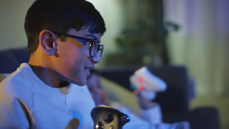 Close-Up-Of-Young-Boy-At-Home-Celebrating-Playing-With-Computer-Games-Console-On-TV-Holding-Controllers-Late-At-Night-1